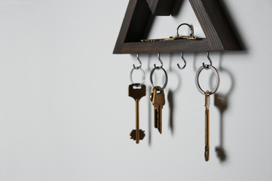 Wooden key holder on light grey wall. Space for text