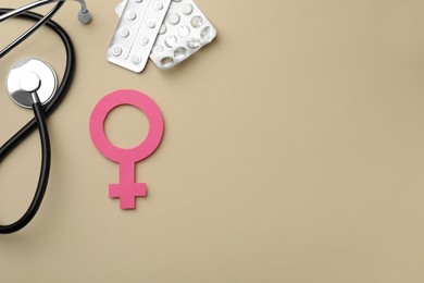 Female gender sign, stethoscope and pills on beige background, flat lay with space for text. Women's health concept