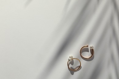 Elegant golden rings with pearls on white table, flat lay. Space for text