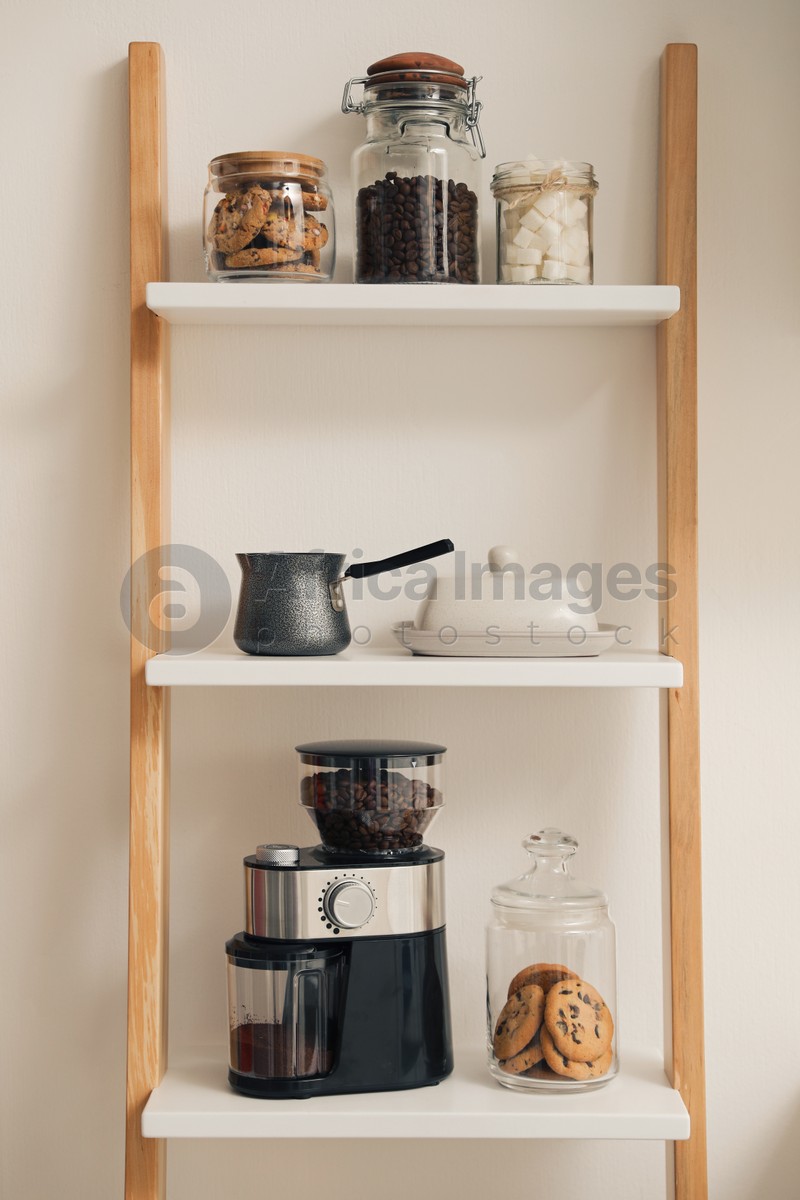 Modern coffee grinder on shelving unit in kitchen