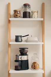 Photo of Modern coffee grinder on shelving unit in kitchen