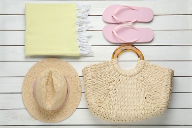 Beach bag, towel, straw hat and flip flops on white wooden background, flat lay