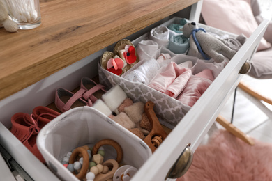 Modern open chest of drawers with baby clothes and accessories in room, closeup