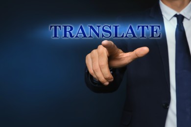 Man pointing at virtual model of word TRANSLATE against dark blue background, closeup