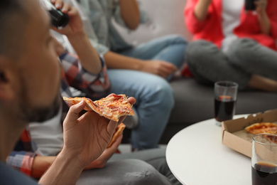 Man eating pizza with friends indoors, closeup