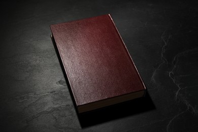 Photo of One old hardcover book on black textured table