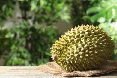 Ripe durian on wooden table against blurred background. Space for text