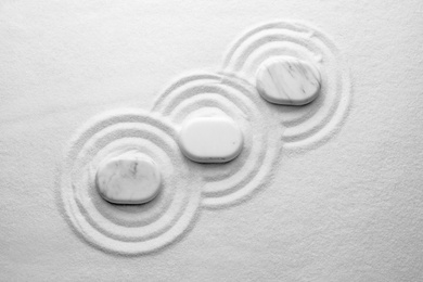 White stones on sand with pattern, flat lay. Zen, meditation, harmony