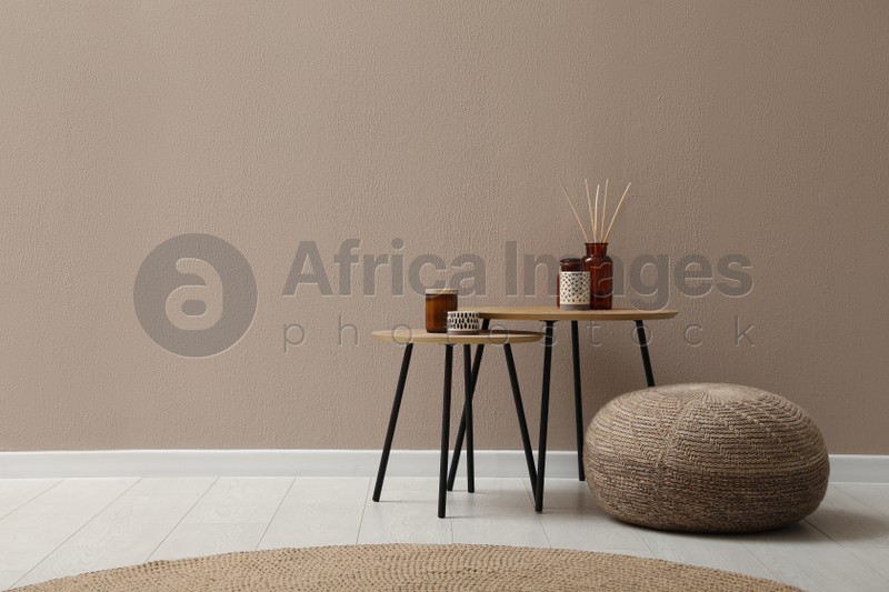 Knitted pouf and decor elements near beige wall indoors. Space for text