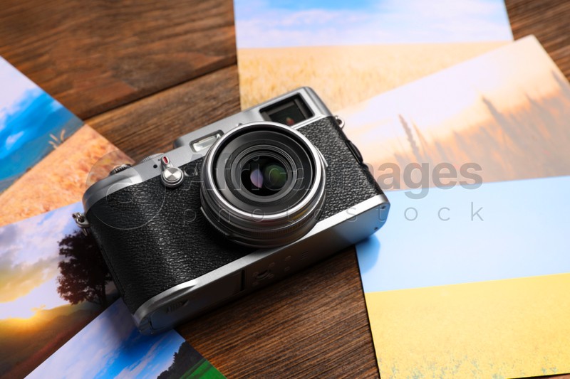 Photo of Vintage photo camera and beautiful printed pictures on wooden table. Creative hobby