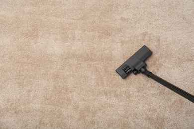 Photo of Removing dirt from carpet with modern vacuum cleaner indoors, top view. Space for text