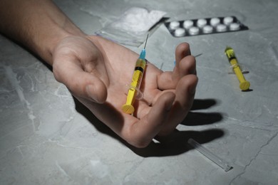 Photo of Man with syringe on grey marble table, closeup. Drug addiction