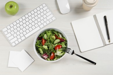 Photo of Bowl of tasty food, keyboard, fork, apple and notebook on white wooden table, flat lay. Business lunch