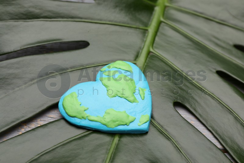 Happy Earth Day. Planet made of plasticine on green leaf, closeup