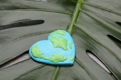 Photo of Happy Earth Day. Planet made of plasticine on green leaf, closeup