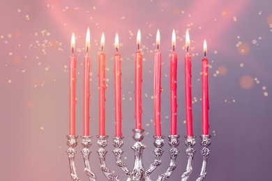 Silver menorah with burning candles on color background, closeup. Hanukkah celebration