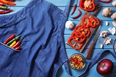 Flat lay composition with denim apron and different ingredients on light blue wooden table