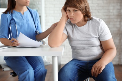 Emotional overweight boy consulting with doctor in clinic
