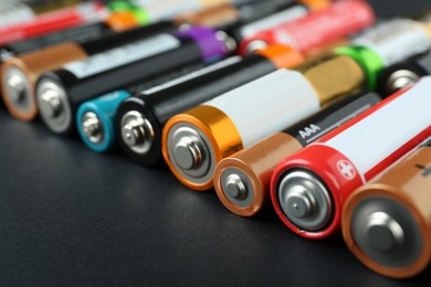 Many different batteries on black background, closeup
