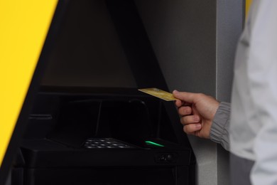Man with debit card using cash machine for money withdrawal outdoors, closeup