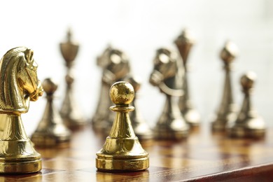 Chessboard with game pieces on light background, closeup