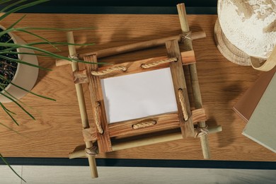 Bamboo frame, plant and globe on wooden table, top view