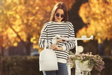 Photo of Young woman with stylish backpack and bicycle on autumn day