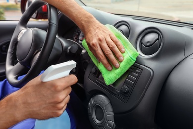 Man cleaning automobile dashboard with duster and detergent, closeup. Car wash service