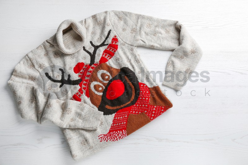 Photo of Warm Christmas sweater with deer on white table, top view