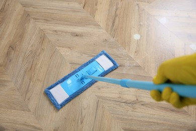 Janitor cleaning parquet floor with mop, closeup