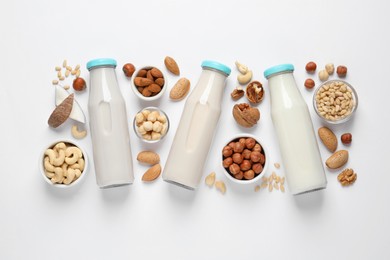 Vegan milk and different nuts on white background, flat lay