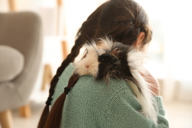 Photo of Little girl with guinea pig at home, back view. Childhood pet