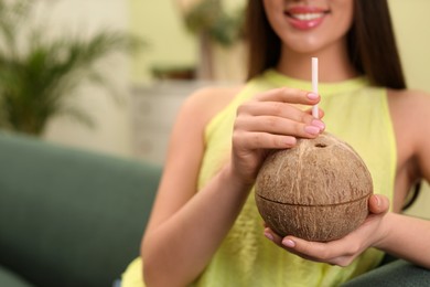 Photo of Young woman with fresh coconut at home, closeup. Exotic fruit