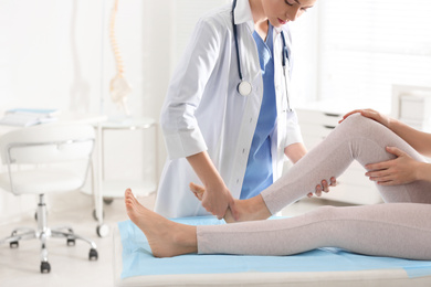 Female orthopedist examining patient's leg in clinic, closeup