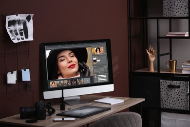 Retoucher's workplace. Computer with photo editor application, camera, smartphone and graphic tablet on table indoors