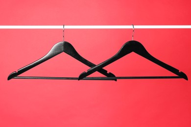 Empty black clothes hangers on metal rail against color background