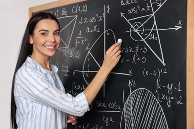 Photo of Happy teacher explaining mathematics at chalkboard in classroom