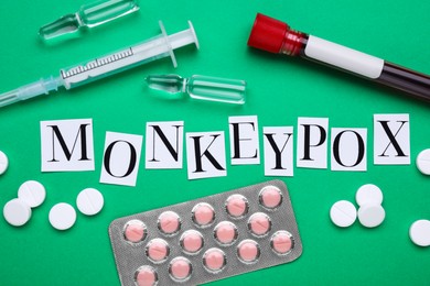 Photo of Flat lay composition with word Monkeypox and medical supplies on green background