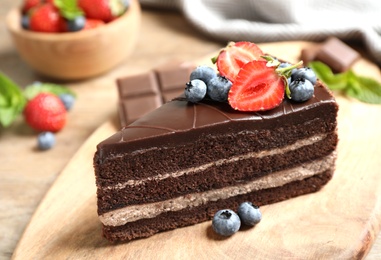 Delicious fresh chocolate cake with berries on wooden table, closeup