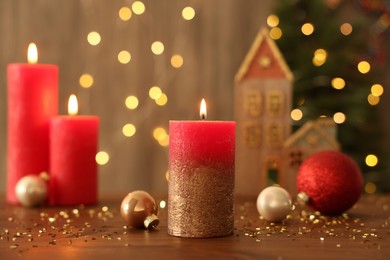 Beautiful burning candles with Christmas decor on wooden table against blurred festive lights