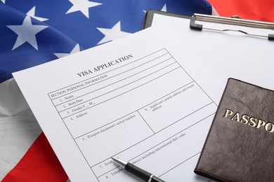Visa application form, clipboard and passport on American flag, closeup