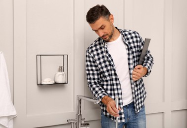Plumber with clipboard checking water tap in bathroom
