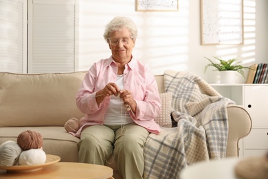 Elderly woman knitting at home. Creative hobby