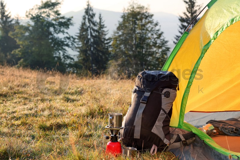 Backpack and tourist equipment near camping tent in nature
