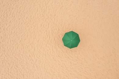 Green beach umbrella on sandy coast, aerial view. Space for text