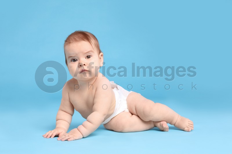 Cute little baby in diaper on light blue background