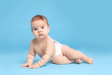 Cute little baby in diaper on light blue background
