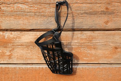 Photo of Black dog muzzle hanging near wooden fence
