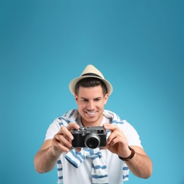 Male tourist taking picture against turquoise background, focus on camera