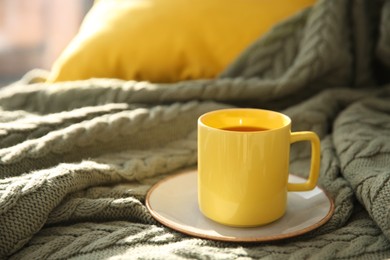 Cup of aromatic tea on green blanket, space for text